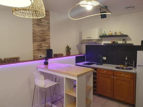 une cuisine avec éclairage violet, table et chaises dans l'établissement La Villa Juliette L'Etoile Filante, à Biville-sur-Mer