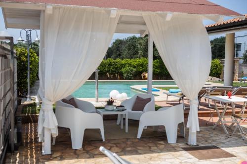 a patio with white furniture and a pool at Ellea Resort in San Michele Salentino