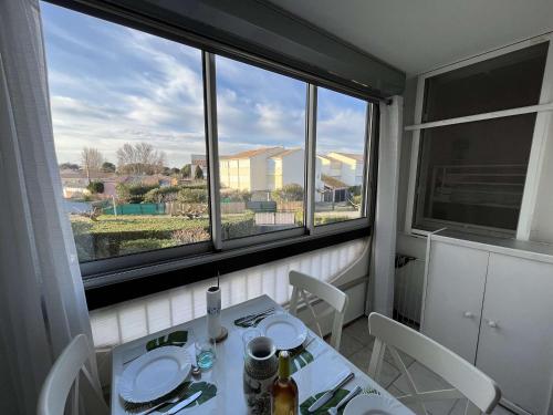 une salle à manger avec une table et une grande fenêtre dans l'établissement Appartement rénové avec loggia ensoleillée, proche plage, parking inclus, quartier calme - FR-1-387-191, à Marseillan