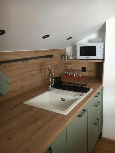 een keuken met een witte wastafel en een magnetron bij Bergbauernwirt im Landhaus Bolgental in Bolsterlang