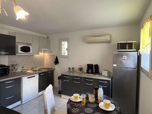 une cuisine avec une table et un réfrigérateur dans l'établissement Maison de vacances climatisée avec terrasse, parking privé, proche plage et commerces - FR-1-387-190, à Marseillan