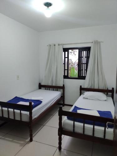 2 Betten in einem Zimmer mit Fenster in der Unterkunft Apartamento de hospedagem-calendula in Joinville