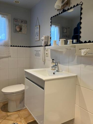a bathroom with a sink and a toilet and a mirror at Hôtel de la Côte Fleurie in Deauville