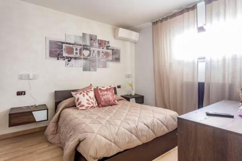 um quarto com uma cama com almofadas cor-de-rosa e uma secretária em Appartamento Esclusivo sulla Spiaggia - 10 minuti dall'Aeroporto em Fiumicino