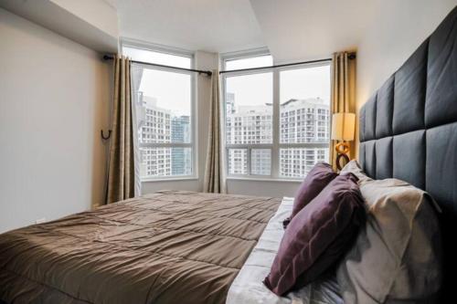 - une chambre avec un grand lit et une grande fenêtre dans l'établissement Luxurious Condominium near Celebration Square, à Mississauga
