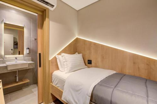 Dormitorio pequeño con cama y lavamanos en Fast Sleep Suites by Slaviero Hoteis - Hotel dentro do Aeroporto de Guarulhos - Terminal 2 - desembarque oeste en Guarulhos