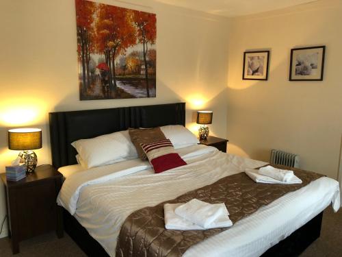 ein Bett in einem Schlafzimmer mit zwei Lampen und einem Gemälde in der Unterkunft The Lethbridge Arms in Taunton