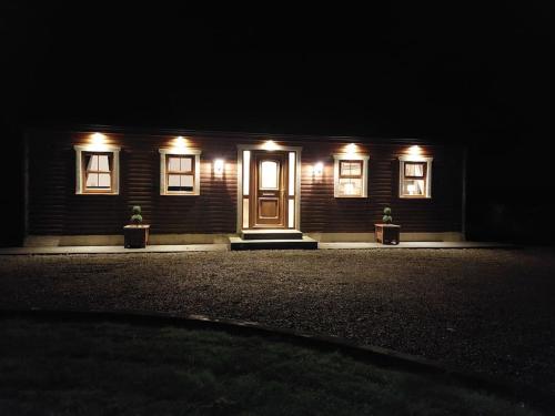 a house with lights on the front of it at night at Luxurious Log Cabin with lay-z spa hot tub in Ballina