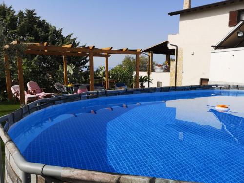 a large swimming pool with a wooden pergola next to a house at La Rosa Rossa in Sciacca