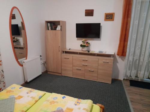 a bedroom with a bed and a dresser with a television at Holiday Apartmanház in Zalakaros