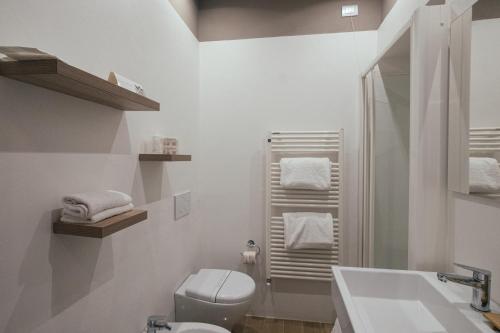 a white bathroom with a toilet and a sink at Bosone Palace in Gubbio