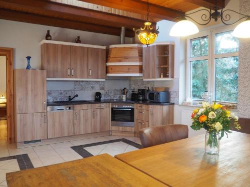 una cocina con armarios de madera y una mesa con un jarrón de flores en Villa Landidyll mit separatem Wellness-Bereich, en Joachimsthal