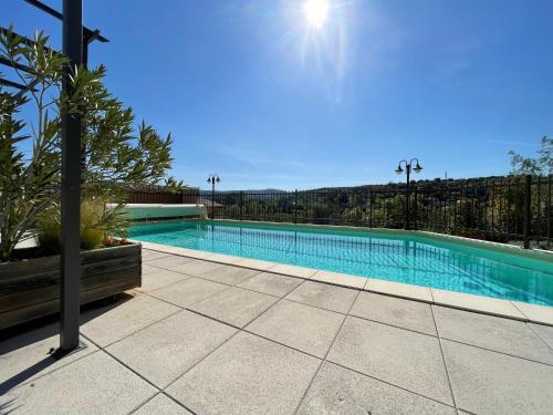 a large swimming pool with the sun in the sky at Gîtes Le Bouzet in Salavas