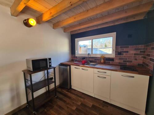 une cuisine avec des placards blancs et un mur en briques dans l'établissement Studio de 35 m2, à Parentis-en-Born