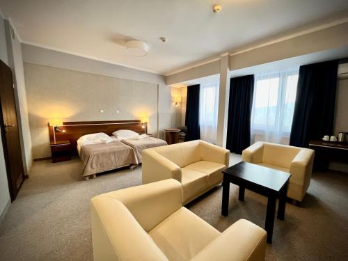 Hotel Szyndzielnia في بييلسكو بياوا: غرفه فندقيه بسرير واريكه وكراسي