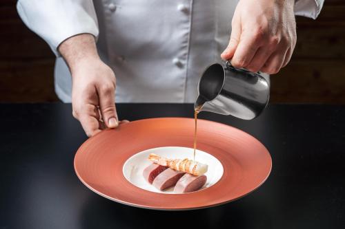 a person pouring mustard on a plate of food at Alpstyle Hotel Albolina Wellness & Beauty in Canazei