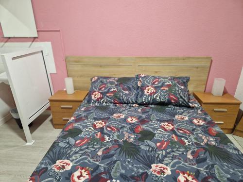 a bedroom with a bed with a floral comforter at PENSION ZEUS in Valladolid