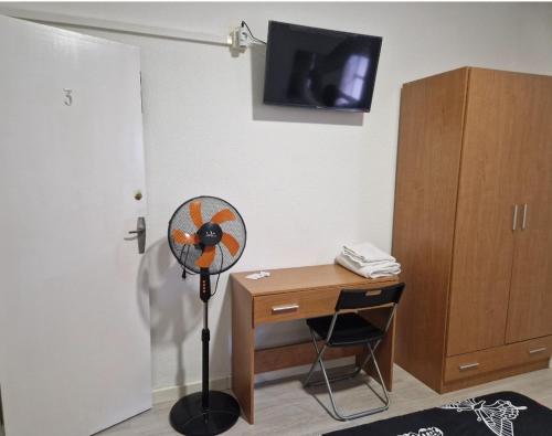Habitación con escritorio y ventilador junto a un armario. en PENSION ZEUS en Valladolid