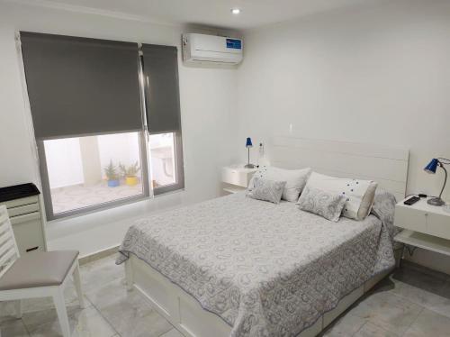 Habitación blanca con cama y ventana en Liniers 14 en Tandil