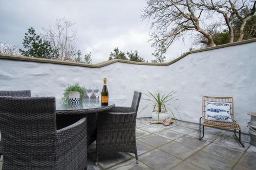 a patio with a table with chairs and a bottle of wine at The Old Spa - 2 Bedroom Cottage - Pleasant Valley in Stepaside