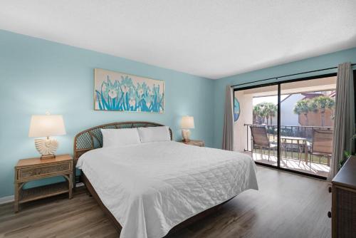 um quarto azul com uma cama e uma varanda em Edgewater Golf Villa 2110 em Panama City Beach