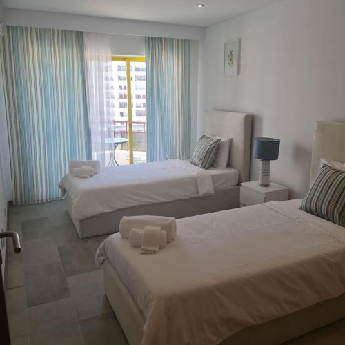 a hotel room with two beds and a balcony at MARIACAST CLUBE DA PRAIA DA ROCHA in Portimão