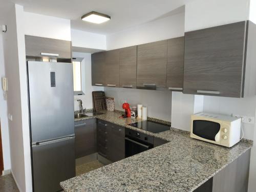 a kitchen with a refrigerator and a microwave on a counter at Ca Vicent in Calpe