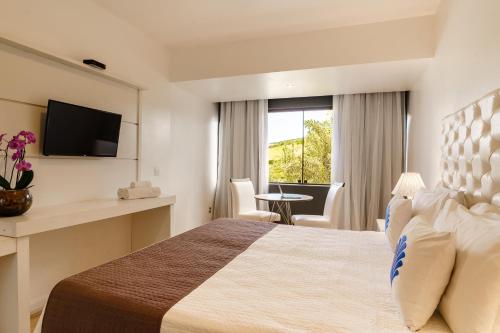 a hotel room with a bed and a window at Greco Hotel in Búzios