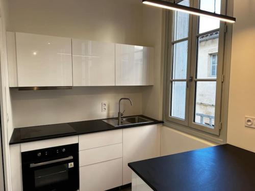 a kitchen with white cabinets and a sink and a window at Le Sainte-Ursule in Montpellier