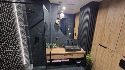La salle de bains est pourvue d'un lavabo et d'un miroir. dans l'établissement Apartament Czarna Perła z duzym tarasem 75m2 na dachu i garazem podziemnym NEW, à Kielce