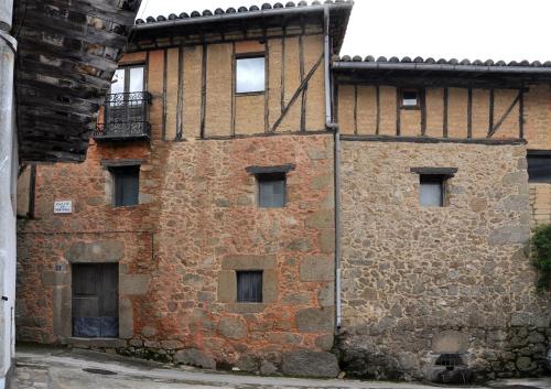 um antigo edifício de tijolos com janelas e uma varanda em El jazmín de la Fuente casa rural em Guijo de Santa Bárbara