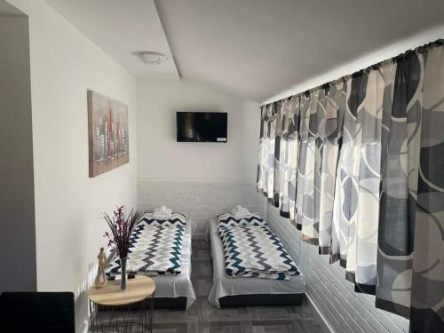 a room with two beds and a tv on a wall at LIKe A cottage in Perušić