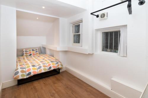 a white bedroom with a bed and two windows at Cosy flat in leafy London in London