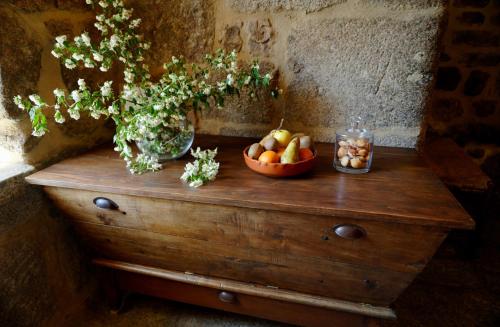 een houten tafel met een fruitschaal en een vaas met bloemen bij Le petit château du Villard in Le Malzieu Forain