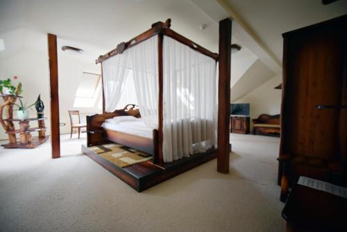 a bedroom with a canopy bed with curtains at Camelot Club Hotel in Vác