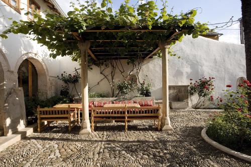 a patio with two benches and a pergola with plants at Bosnian National Monument Muslibegovic House in Mostar