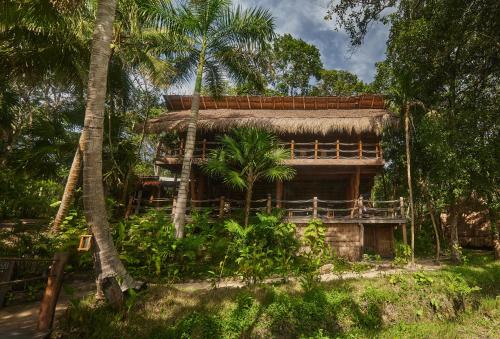 una casa con techo de paja y palmeras en Our Habitas Bacalar en Bacalar