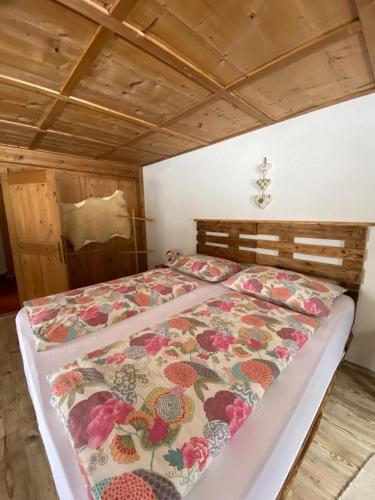 a bed with a floral comforter in a bedroom at Gästehaus Hoamat'l in Bach