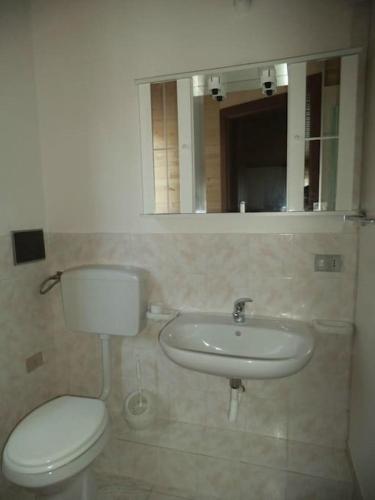 uma casa de banho com um WC, um lavatório e um espelho. em Mansarda M&M SX em Castellammare del Golfo