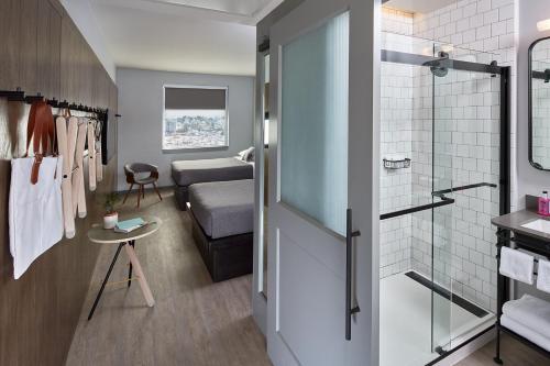 a bathroom with a shower and a bedroom at MOXY Denver Cherry Creek in Denver