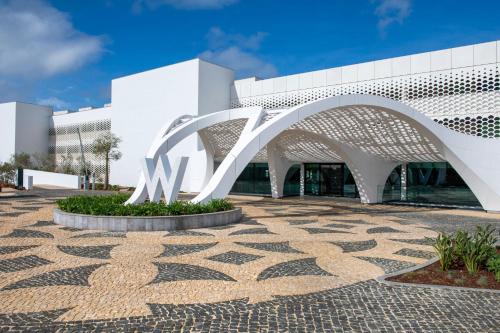 a white building with a metal archway in front of it at W Algarve in Albufeira