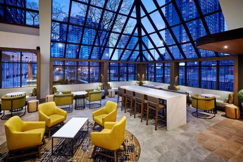 a lobby with yellow chairs and a large glass ceiling at Delta Hotels by Marriott Toronto Mississauga in Mississauga