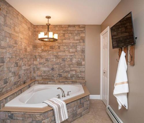 a bathroom with a large tub with a stone wall at Beautiful Modern Farmhouse Style Mins 2 Beach, Winery, Casino, Shopping and More 
