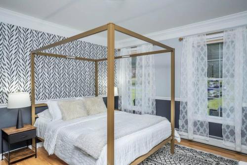 1 dormitorio con cama con dosel y sábanas blancas en Beautiful Modern Farmhouse Style Mins 2 Beach, Winery, Casino, Shopping and More 
