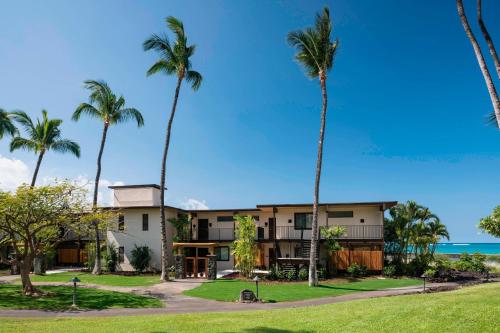 a building with palm trees in front of the ocean at Waikoloa Beach Marriott Resort & Spa in Waikoloa