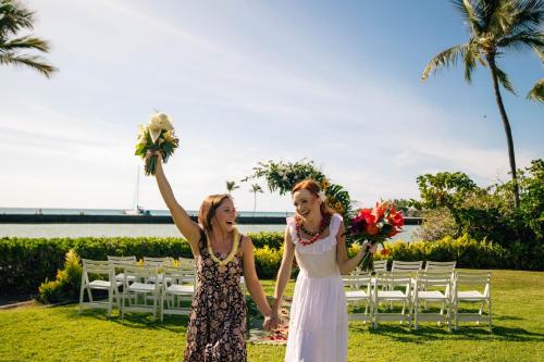 two girls are holding up their bouquets at a wedding at Waikoloa Beach Marriott Resort & Spa in Waikoloa