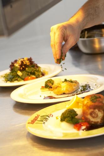 a person reaching for food on plates on a table at Landhotel Haringerhof mit Saunawelt und Naturbadeteich in Grafenhausen
