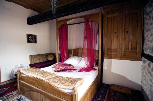 a bedroom with a canopy bed with red curtains at Bosnian National Monument Muslibegovic House in Mostar