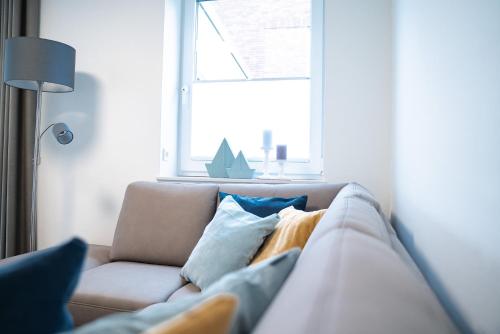a couch with pillows in a living room with a window at Urlaub an der Nordsee - NEU - Ferienhaus Deichliebe in Fedderwarderdeich