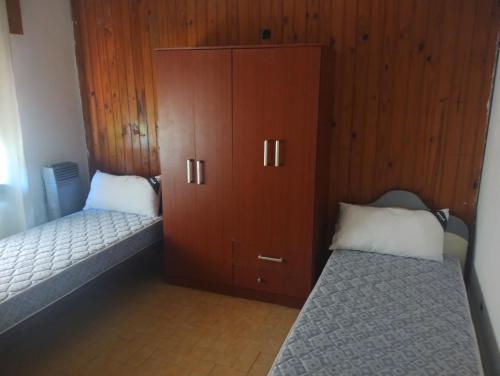 1 dormitorio con 2 camas y un gran armario de madera en Canela House en Huerta Grande